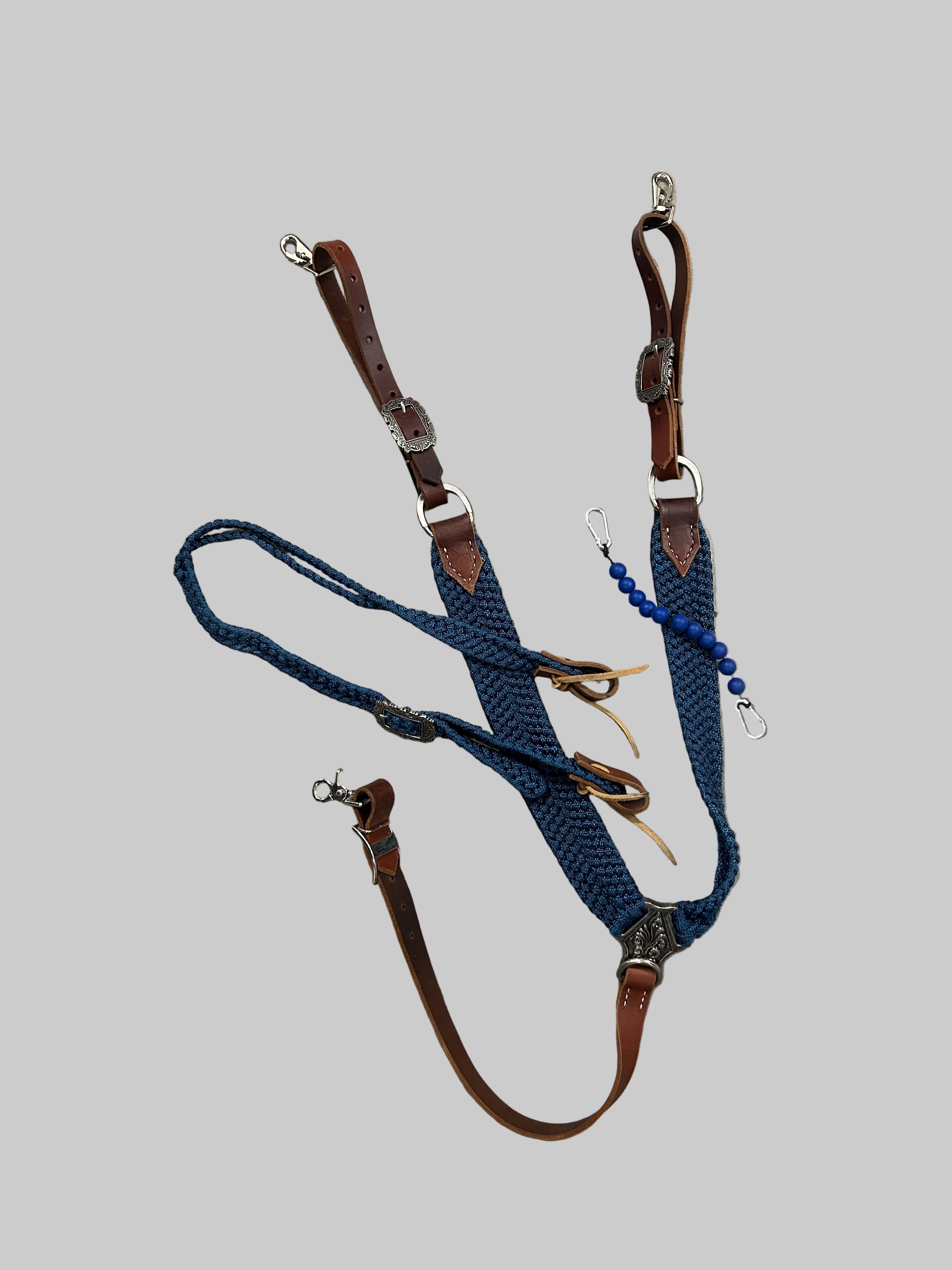 Horse bridle with blue reins and brown leather straps on a tiled floor