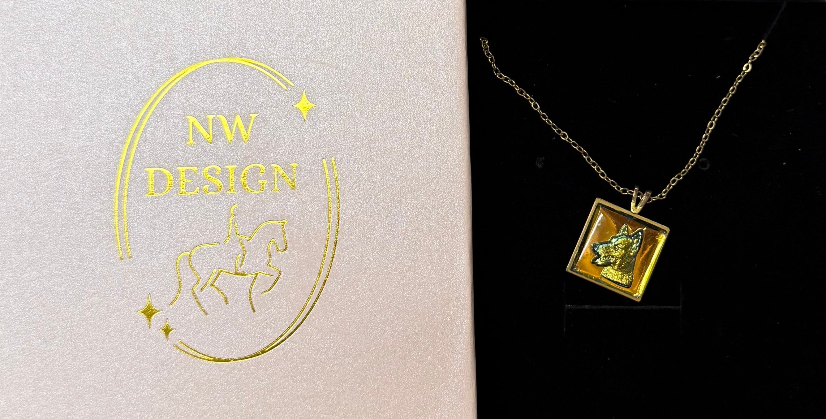 Gold necklace in a pink box on a stone floor