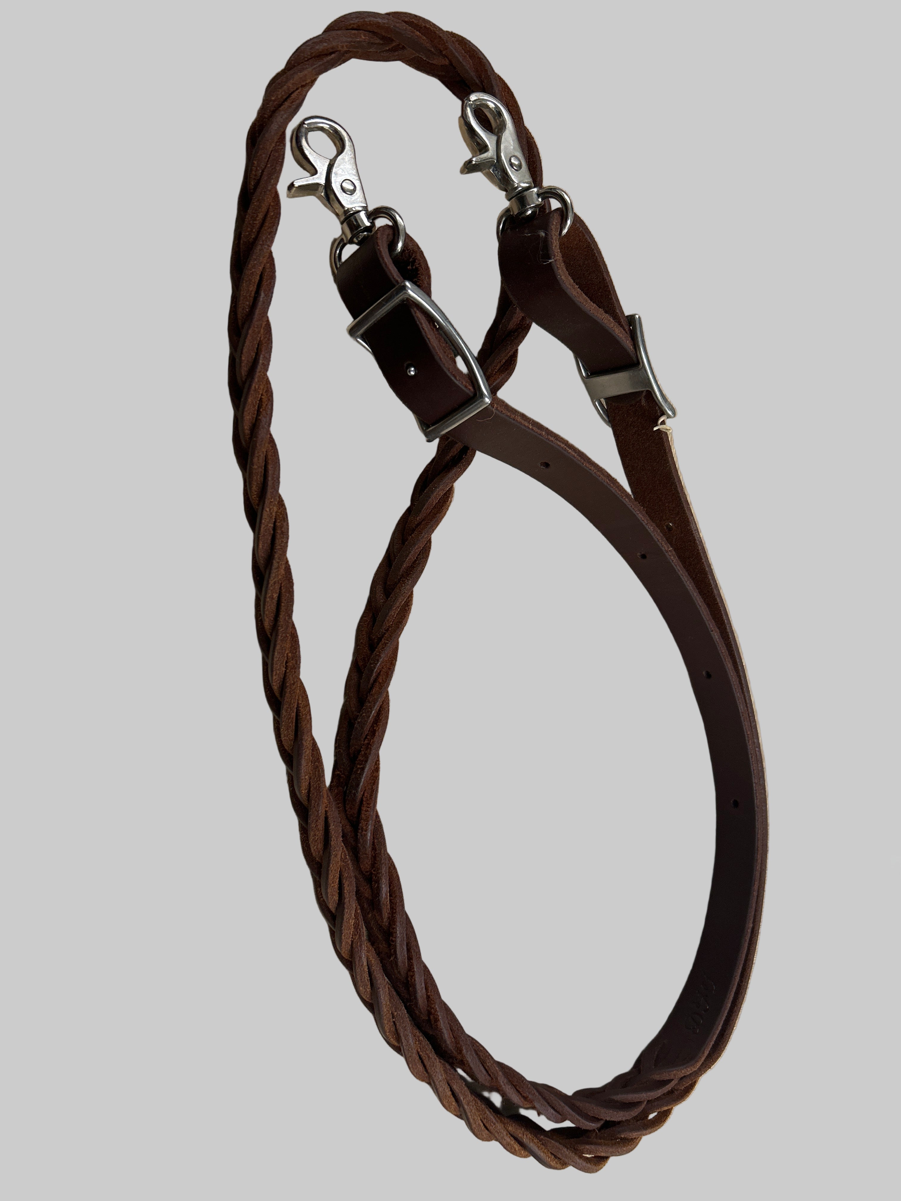 Brown braided leather horse reins on a wooden surface